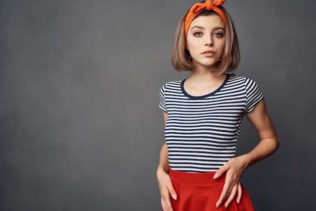 Pretty fashionable woman with orange headband red skirt posing