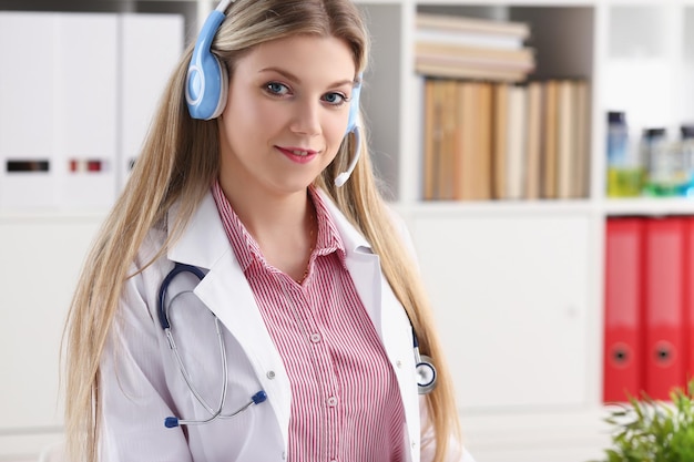 Pretty female blonde doctor talking to patient over wireless headset advises medical problem