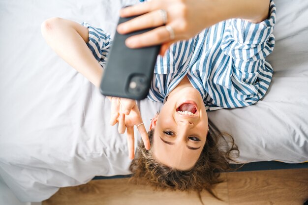 pretty female creating content for social media Influencer in bedroom relaxed having video chat