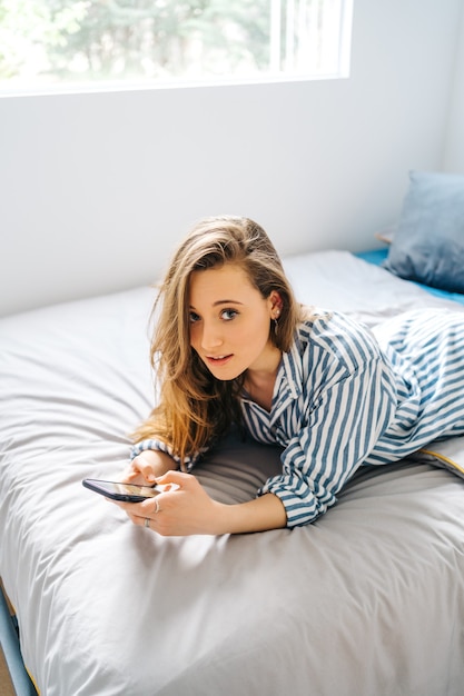 pretty female creating content for social media Influencer in bedroom relaxed having video chat