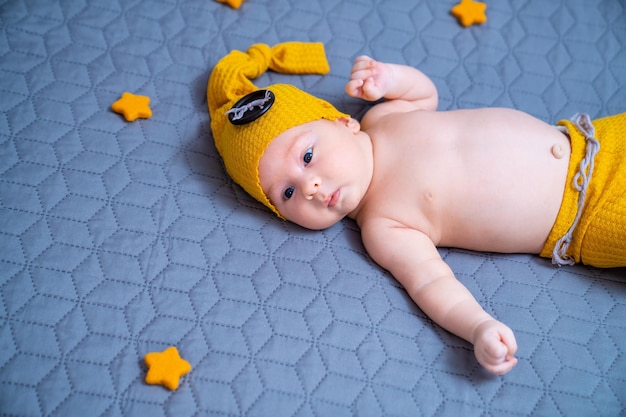 Pretty funny kid in hat lying on blanket Adorable sweet baby in a hat with pompon