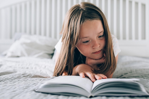 Pretty girl 89 years old lies on bed reading the book Comfort cozy home concept Lifestyle