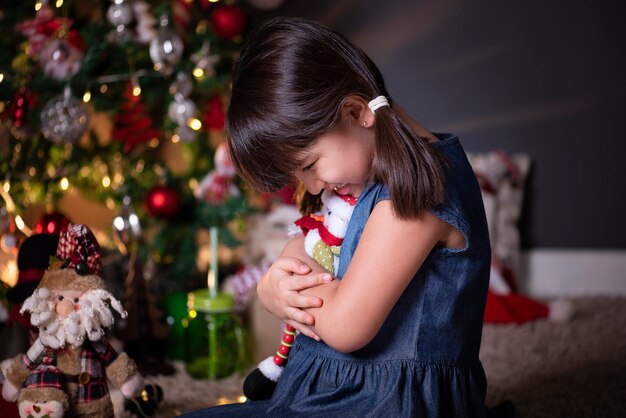 Pretty girl in Christmas decoration hugging a snowman