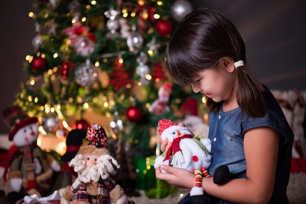 Pretty girl in Christmas decoration playing with snowman