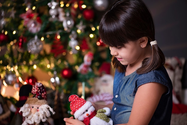 Pretty girl in Christmas decoration playing with snowman