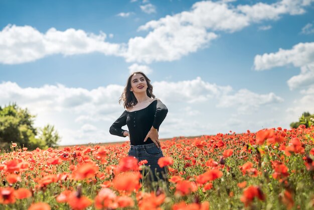 Pretty girl dreaming and enjoy nature at the field of red poppies. summer time