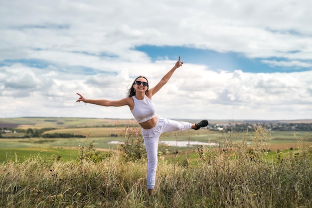 Pretty girl enjoys a warm sunny summer day on a meadow with tall grass