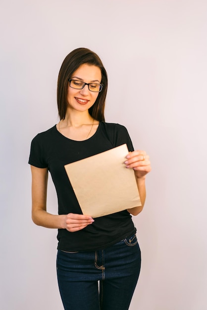 Pretty girl in glasses holds document in hands Paper shit in hands White background