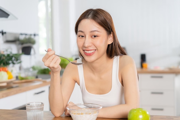 Pretty girl happy meal eating healthy breakfast in morning asian young woman having cereals granola with fresh dairy milk in bowl in kitchen Dieting vegetarian food people concept