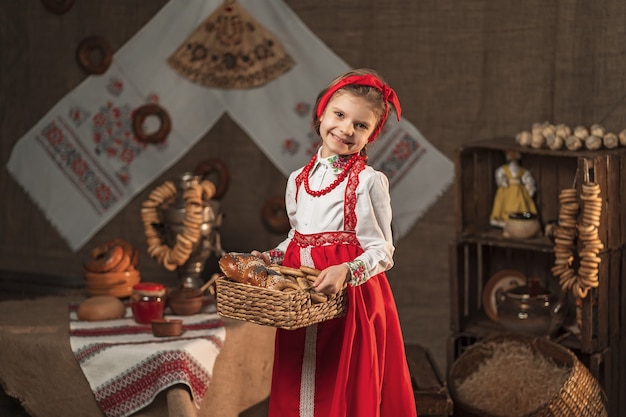 Pretty girl holding basket of bagels and other baking in traditional house