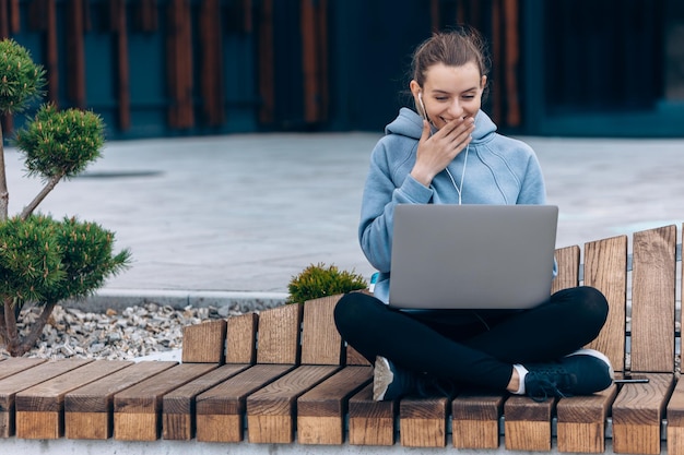 Pretty girl holding laptop outdoors smiling