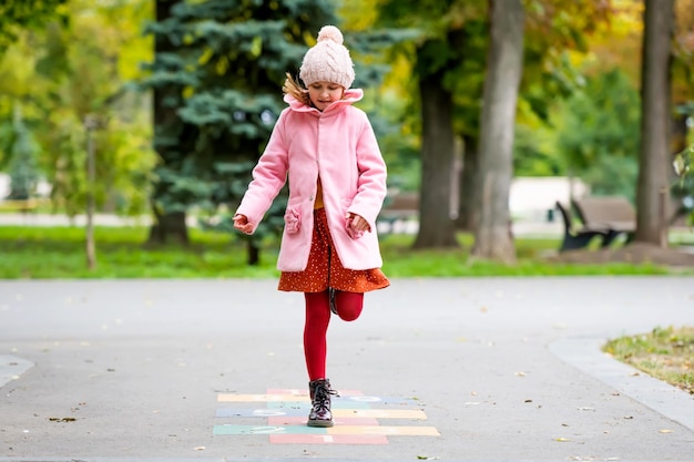 Pretty girl kid jumping at street and playing after school at autumn day happy child portrait outdoo