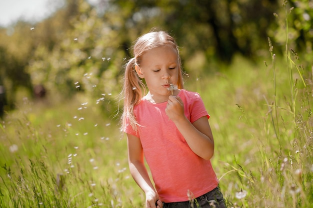 A pretty girl in pink holding a blowball