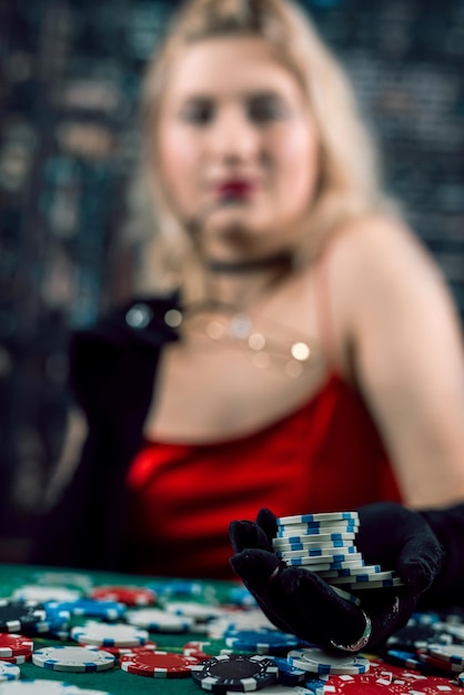 Pretty girl in red dress and hat playing poker