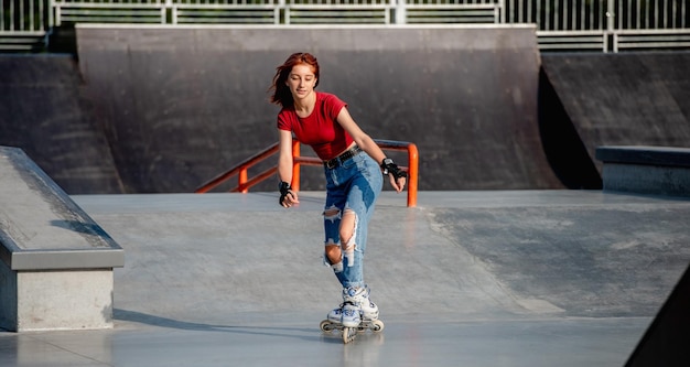 Pretty girl on roller skates riding in the city at park ramp. Female teenager rollerblading outdoors