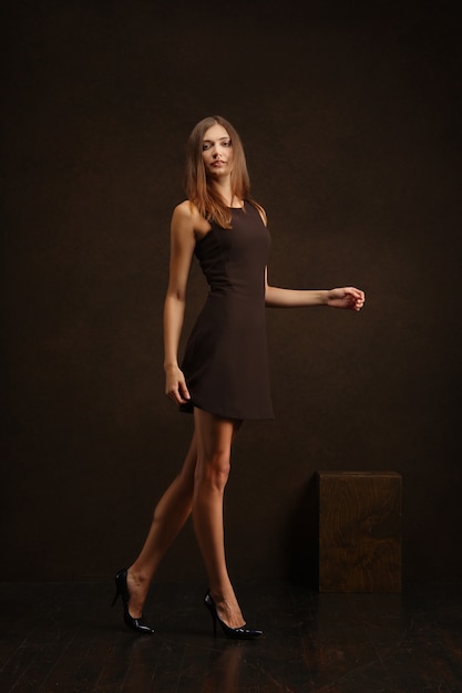 Photo pretty girl in short dress walking along dark wall