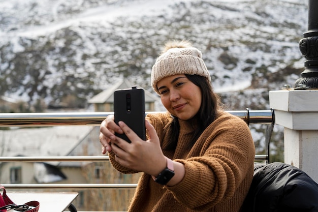 pretty girl smiling taking photos while having a drink in a snowy town in the mountains