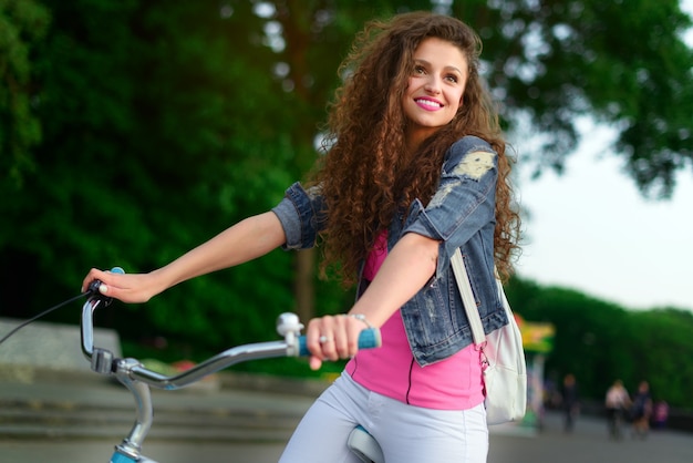 Pretty girl with curly hair on a bike in the city