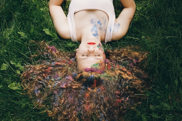 Pretty girl with curly hair lying on the grass with closed eyes