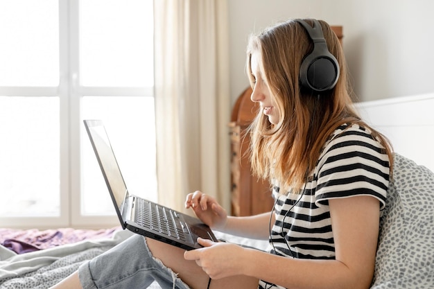 Pretty girl with headphones and laptop in bed