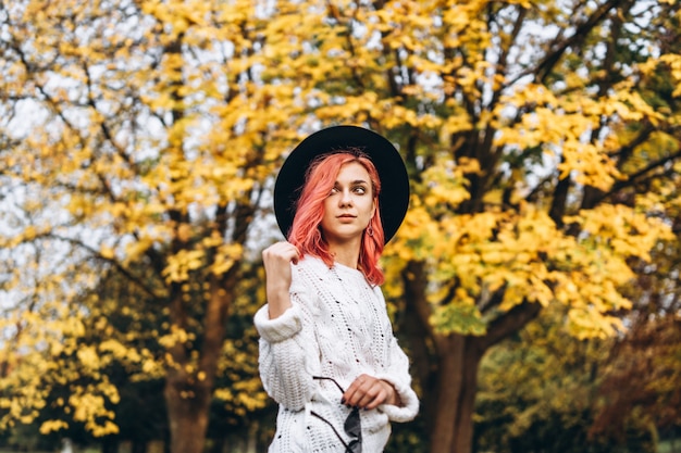 Pretty girl with red hair and hat relaxing in the park, autumn time.