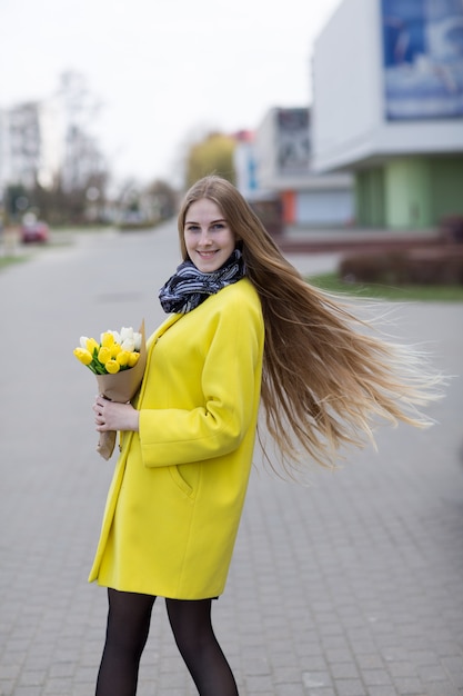 Pretty girl in yellow coat with white and yellow flowers