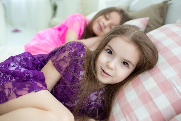 Pretty girls in pink and purple dresses in bed