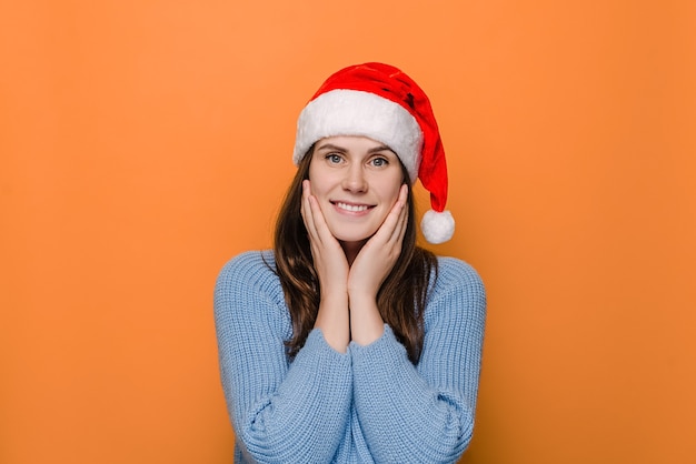 Pretty happy European woman keeps hands on cheeks