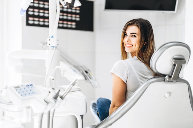 Pretty happy and smiling dental patient sitting in the dental chair at the dental office.