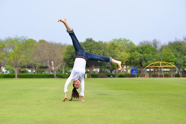 pretty healthy young woman jump and exercise fitness on grass in green park with city in background