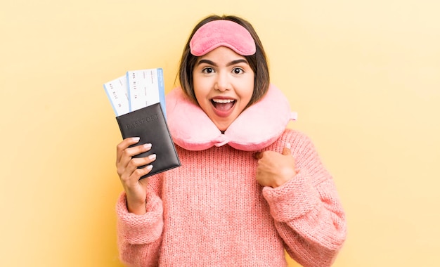 Pretty hispanic girl feeling happy and pointing to self with an excited flight passenger concept