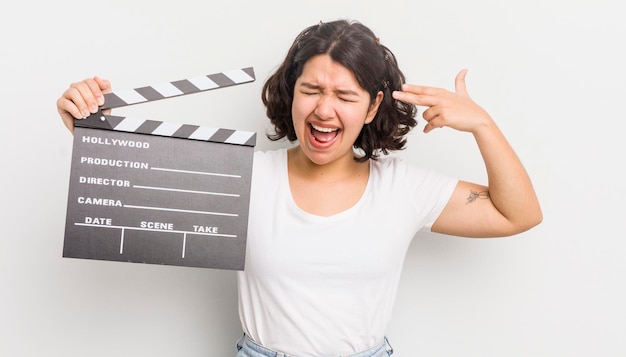 Pretty hispanic girl looking unhappy and stressed suicide gesture making gun sign cinema concept