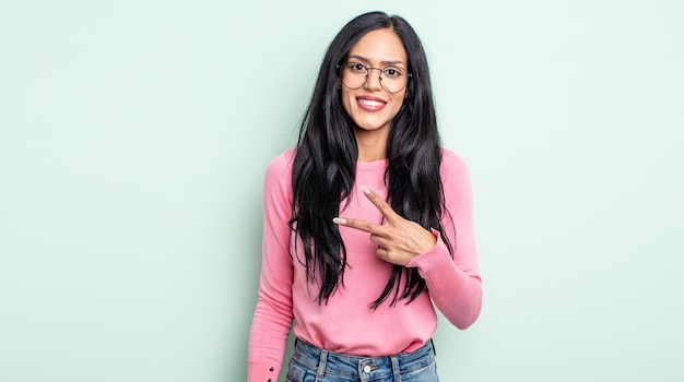 Pretty hispanic woman feeling happy, positive and successful, with hand making v shape over chest, showing victory or peace