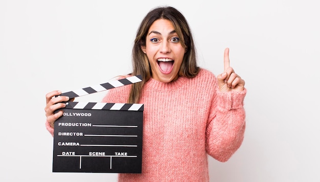 Pretty hispanic woman feeling like a happy and excited genius after realizing an idea cinema clapper concept