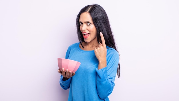 Pretty hispanic woman feeling like a happy and excited genius after realizing an idea empty bowl concept