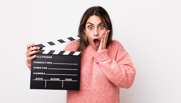 Pretty hispanic woman feeling shocked and scared cinema clapper concept