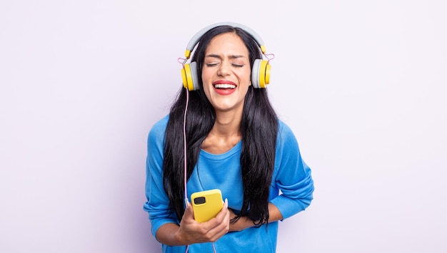 Pretty hispanic woman laughing out loud at some hilarious joke. smartphone and headphones concept