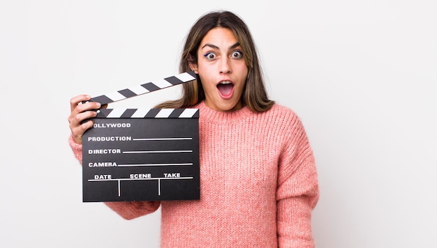 Pretty hispanic woman looking very shocked or surprised cinema clapper concept