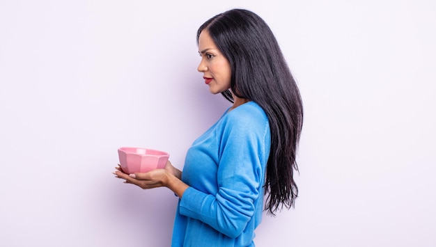 Pretty hispanic woman on profile view thinking, imagining or daydreaming. empty bowl concept