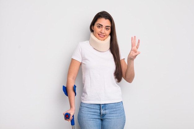 Pretty hispanic woman smiling and looking friendly, showing number three. crash and physical injury concept