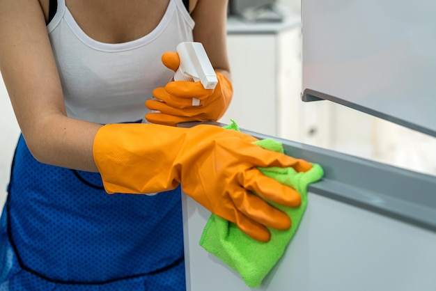 Pretty housewife cleans the surface of the refrigerator cleaning concept