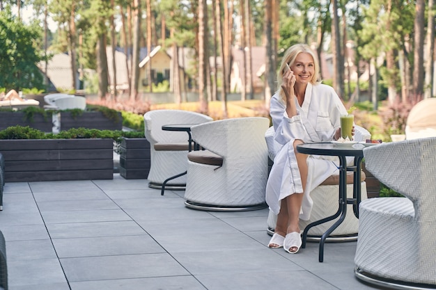 pretty lady talking on her mobile phone while sitting at the terrace of hotel