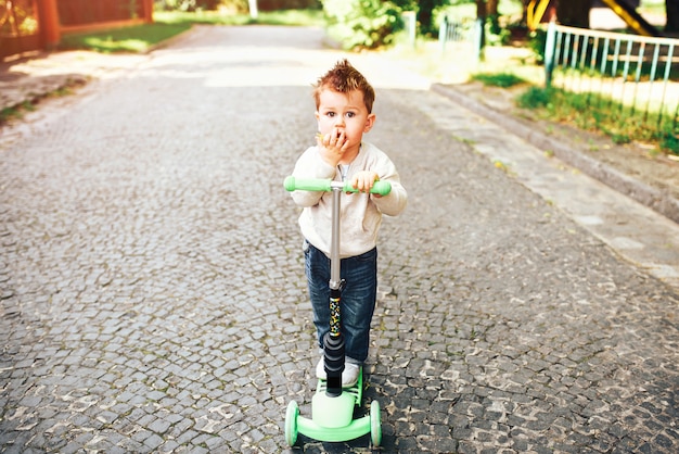 Pretty little boy riding scooter outdoor on the street