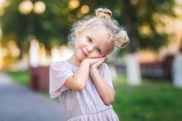 Pretty little cute girl posing for camera in the summer in the park