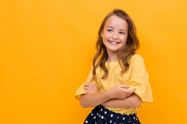 Pretty little girl in beautiful dress rejoices of her life isolated on orange