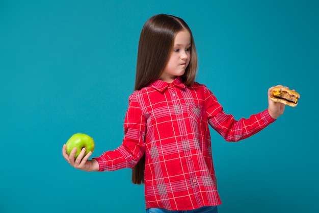 Pretty, little girl in checkered shirt with brunet hair hold burger