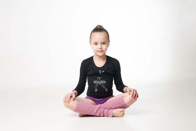 Pretty little girl doing gymnastics over white background