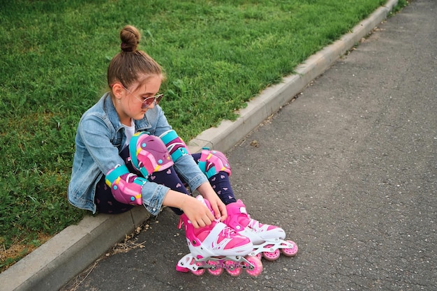 Pretty little girl learning to roller skate on beautiful summer day in a park