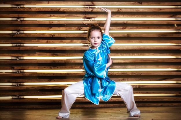 Pretty little girl in the room in sportswear for martial arts is Wushu or kung fu