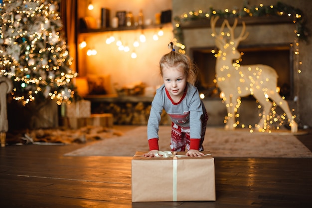 A pretty little girl in traditional pajamas received a Christmas gift